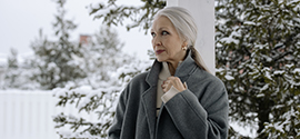 La nonna in cappotto grigio davanti al paesaggio invernale.