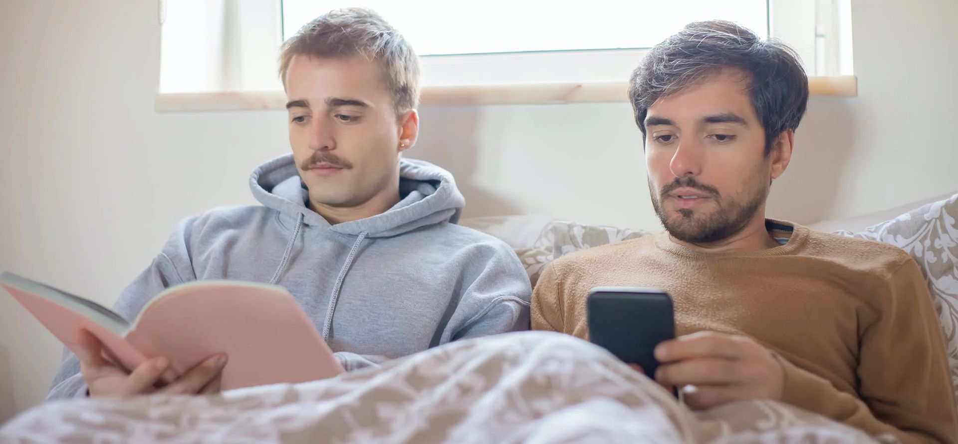 Gay couple reading on the bed.