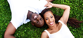 Afroamerický pár leží na trávě.