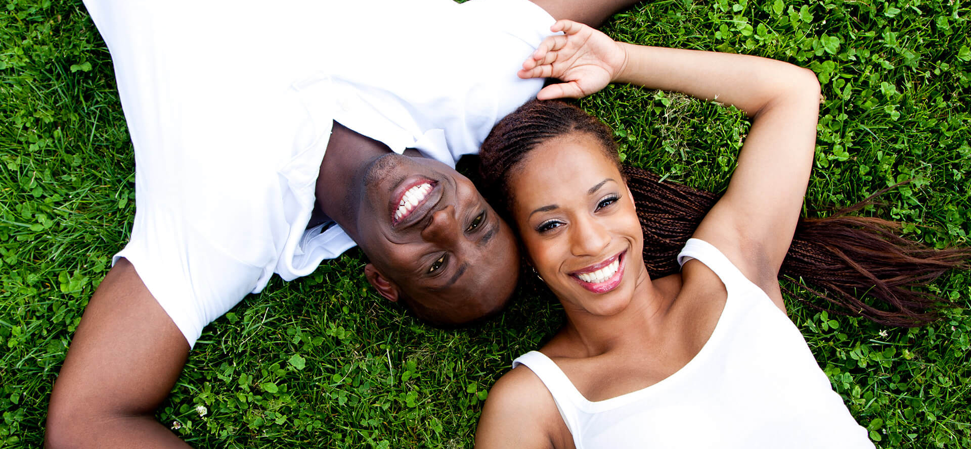 O casal afro-americano está deitado sobre a grama.