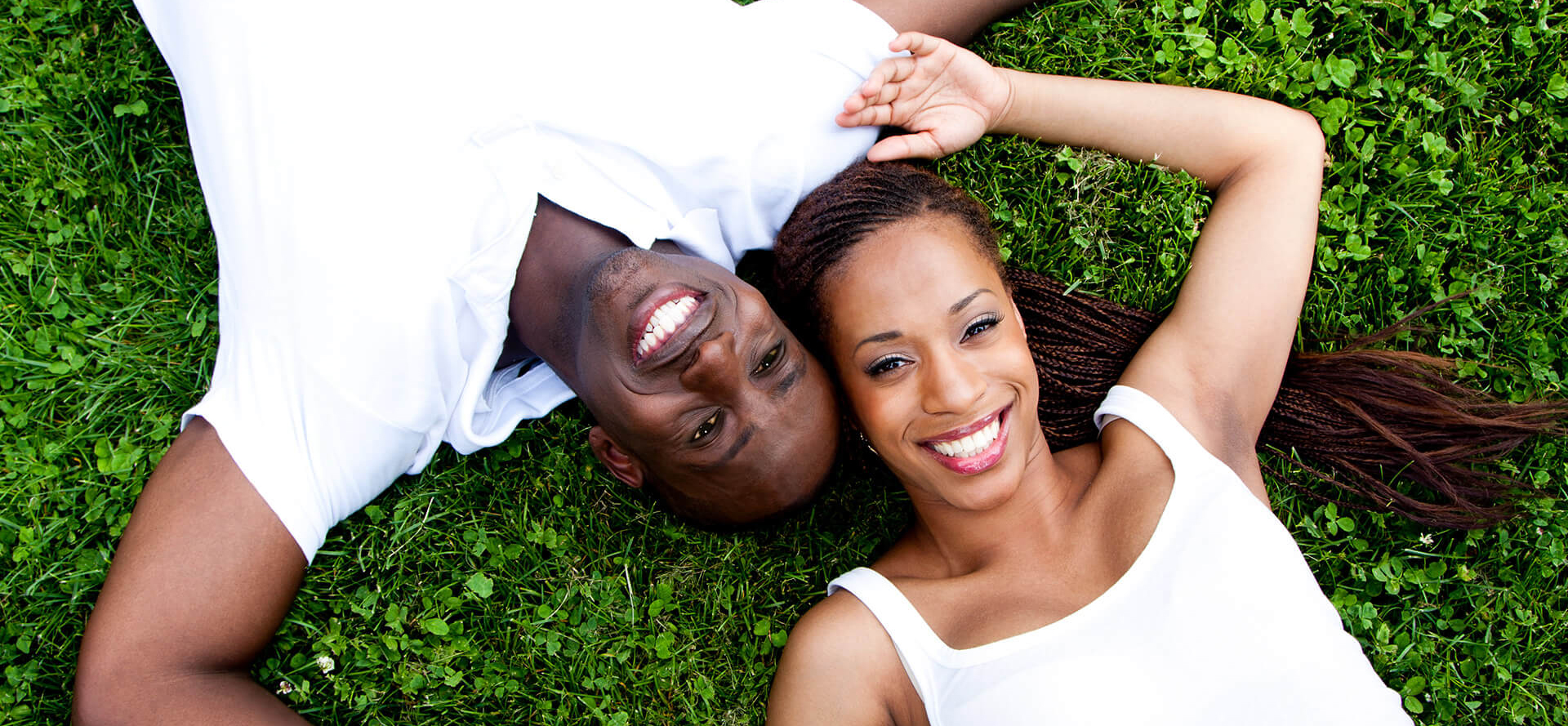 Pareja afroamericana tumbada en la hierba.