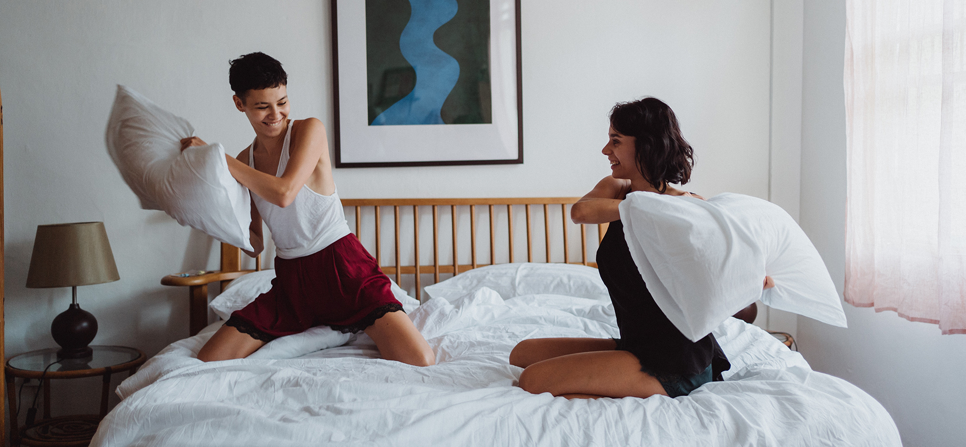 Asexual couple fight with pillows on the bed.