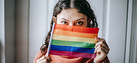 Uma menina bissexual cobre seu rosto com a bandeira LGBT.