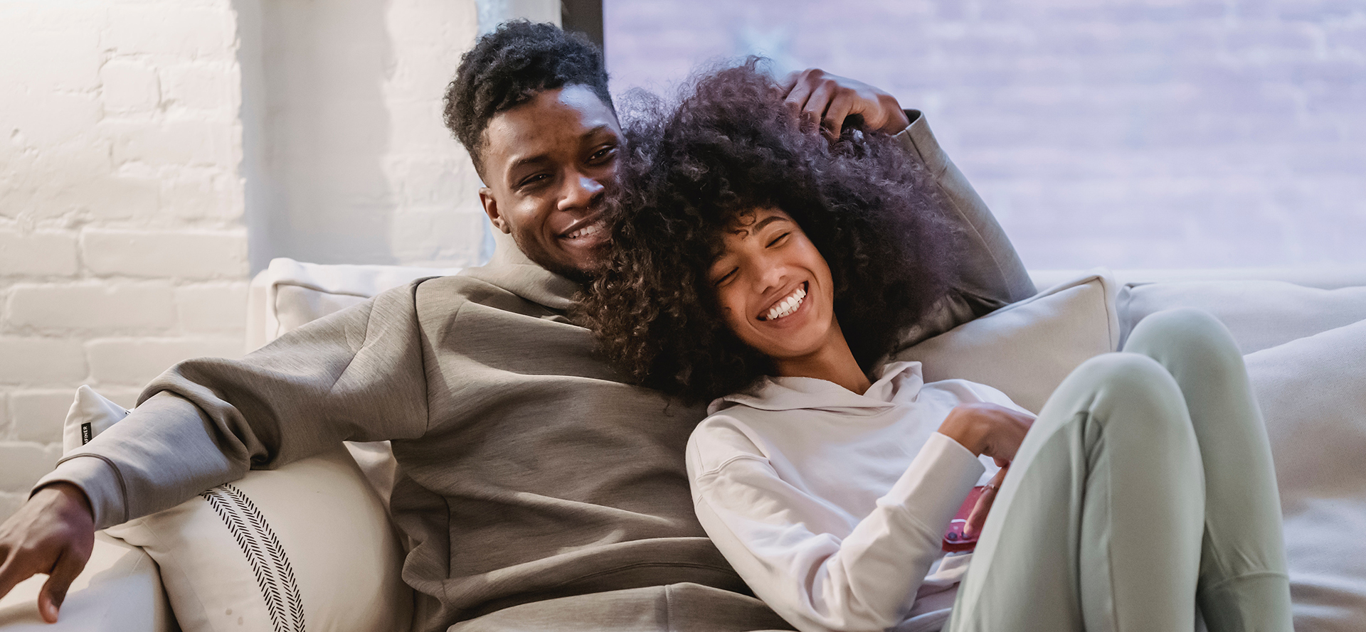 Black couple is lying on the couch.