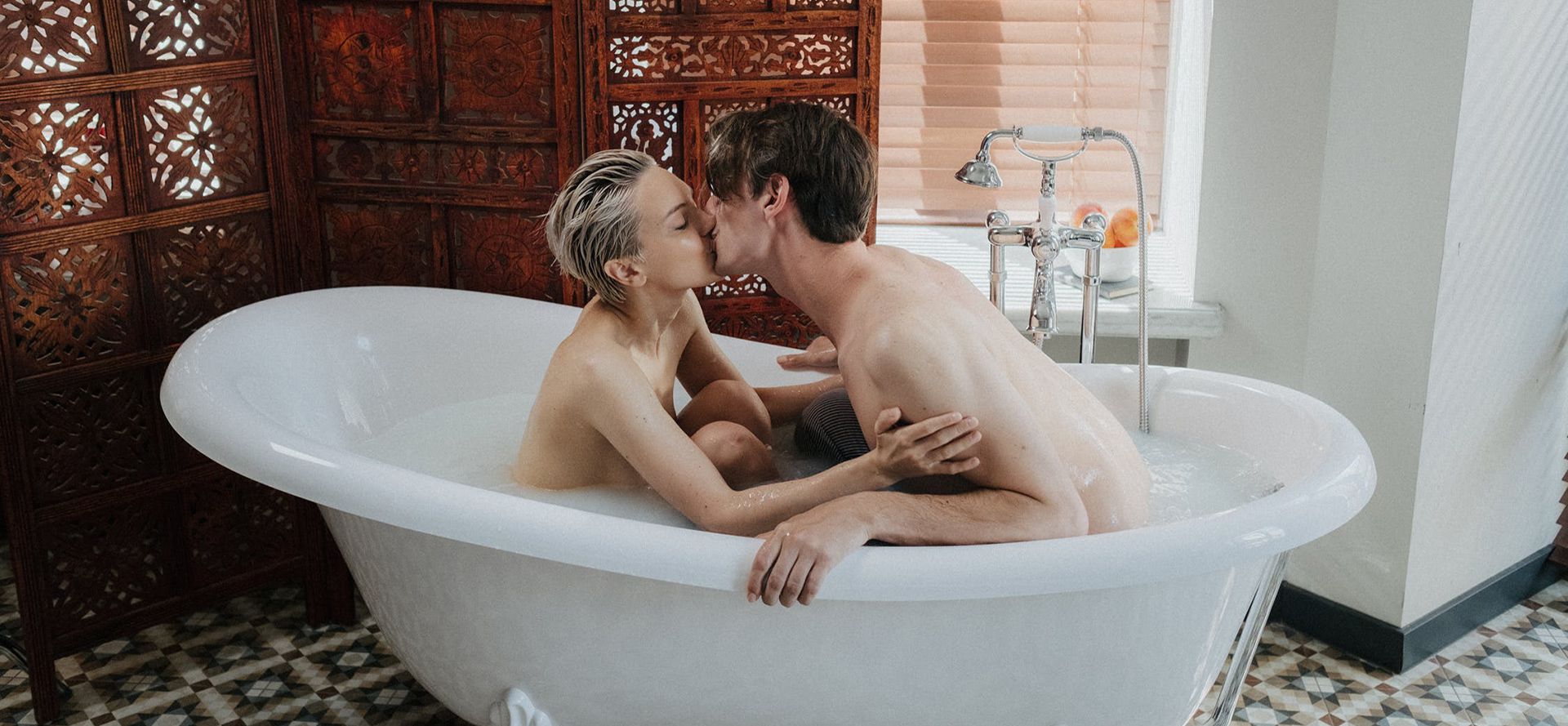 A couple kissing in the bath.