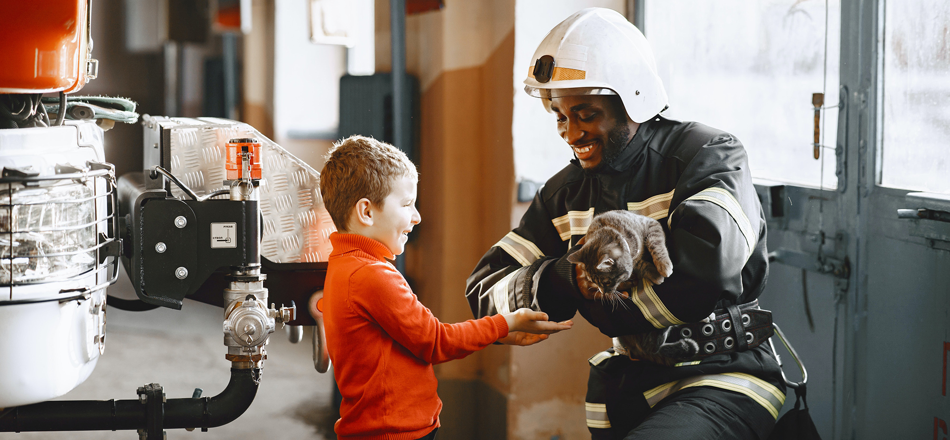 The firefighter returns the rescued kitten to the child.