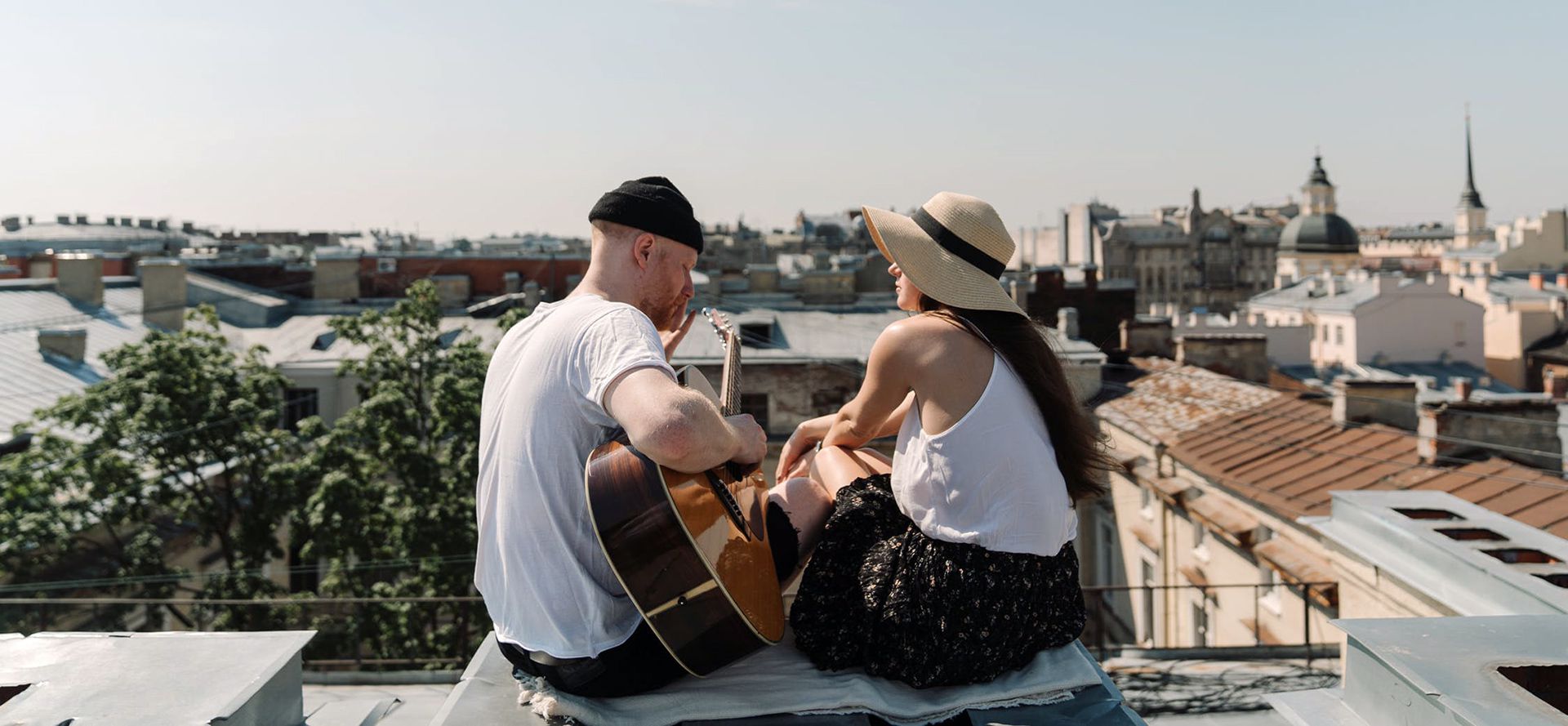 A guy plays guitar for a girl on a rooftop date.