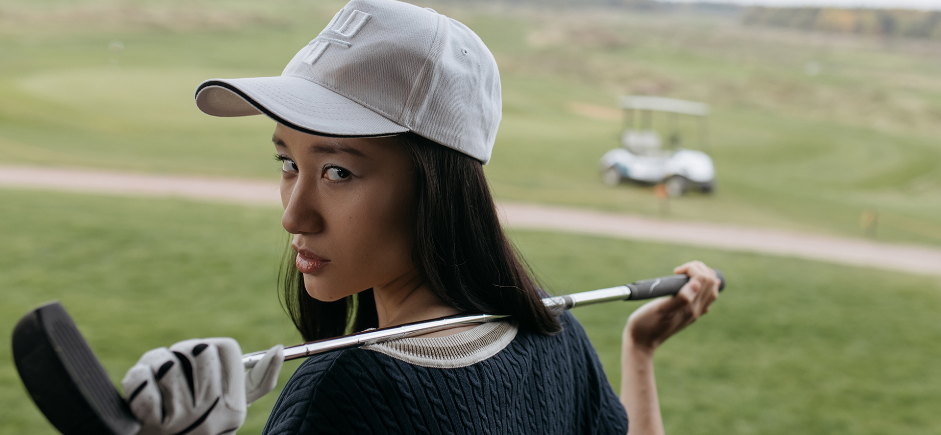 Alleenstaande vrouwelijke golfer poseert met een golfclub.