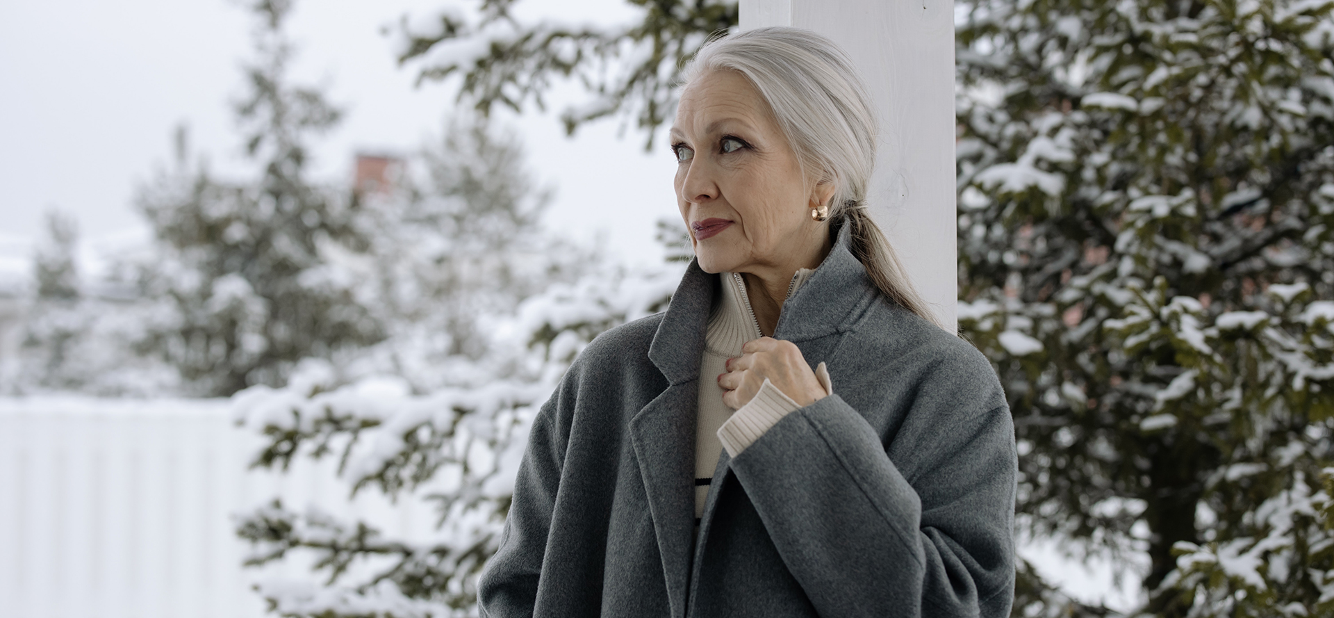 Kış manzarasının önünde gri paltolu büyükanne.
