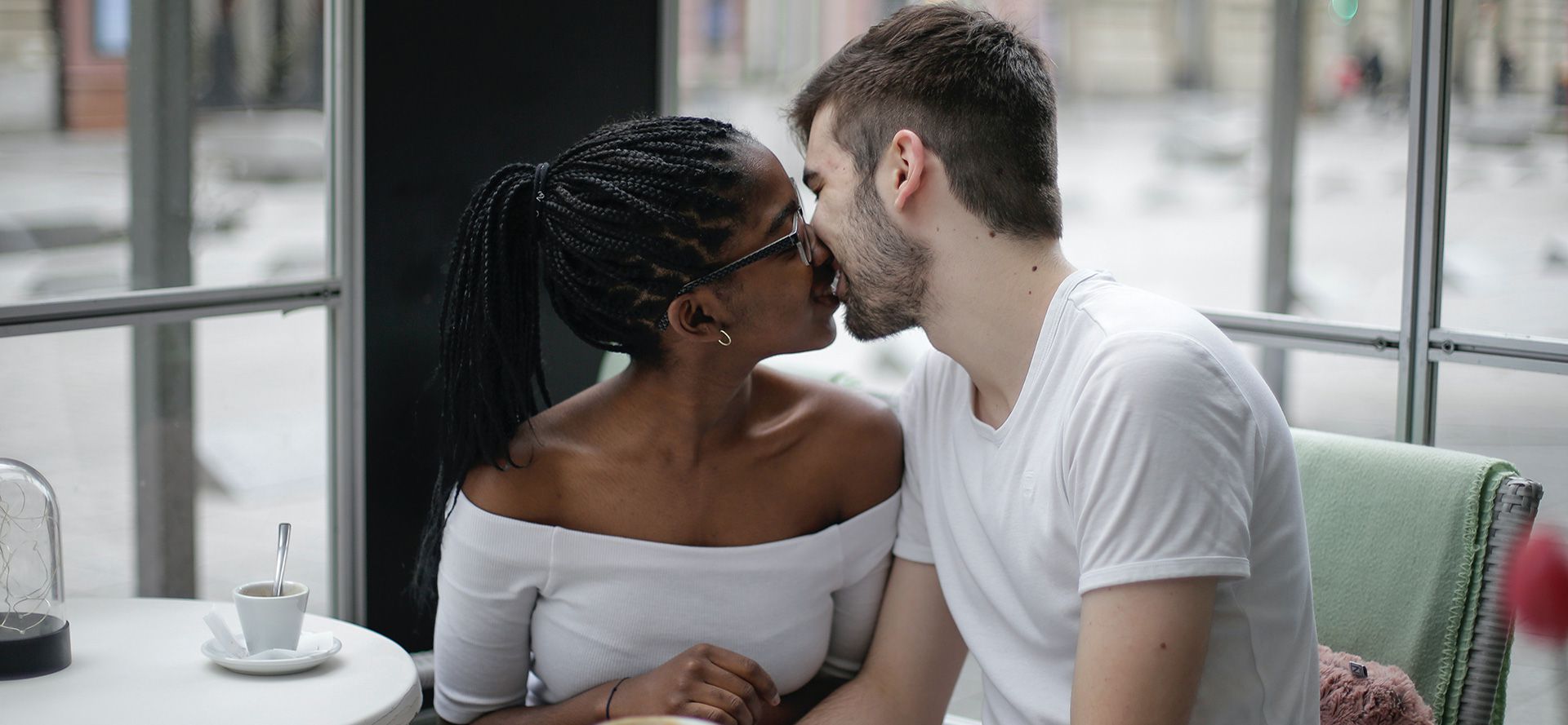 International couple are kissing in cafe.