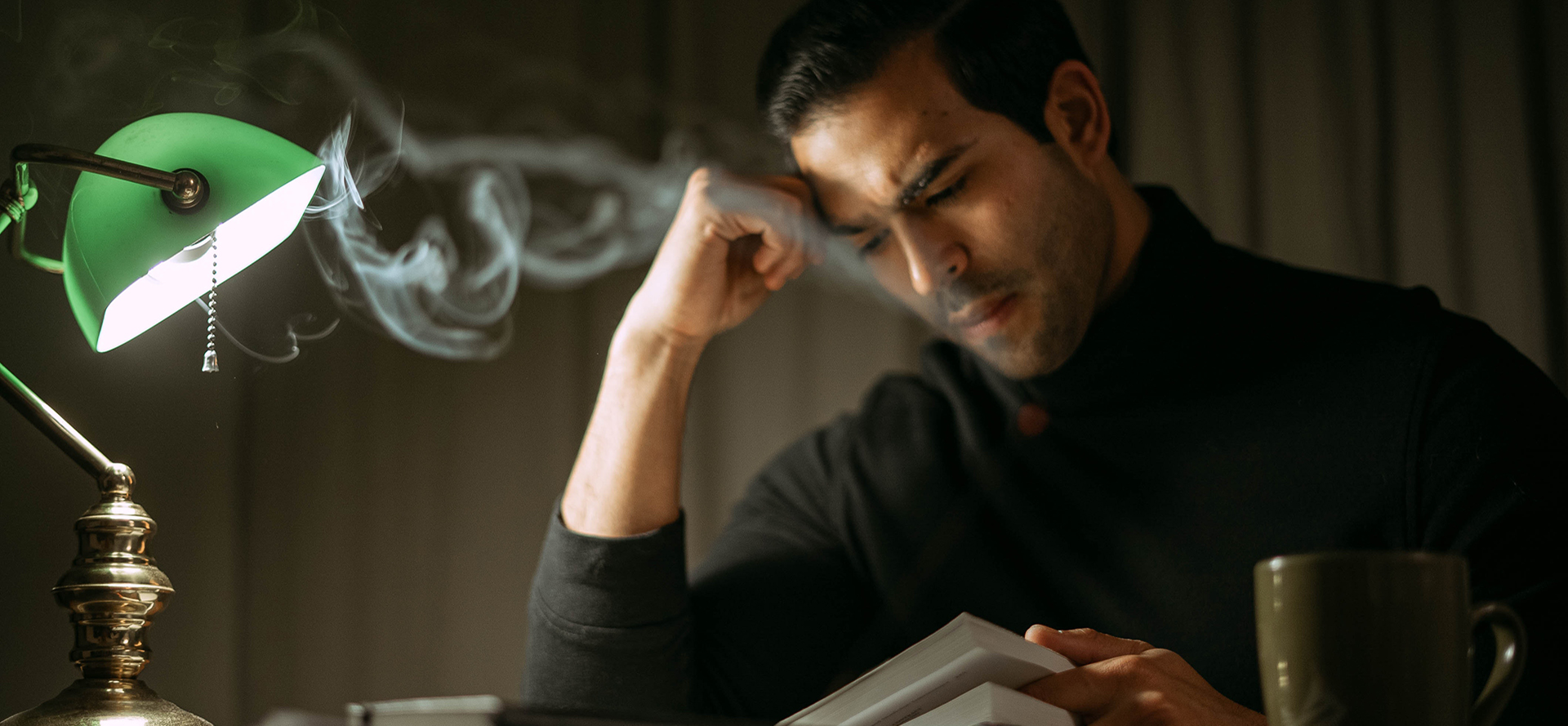 A man in a black shirt is reading a book.