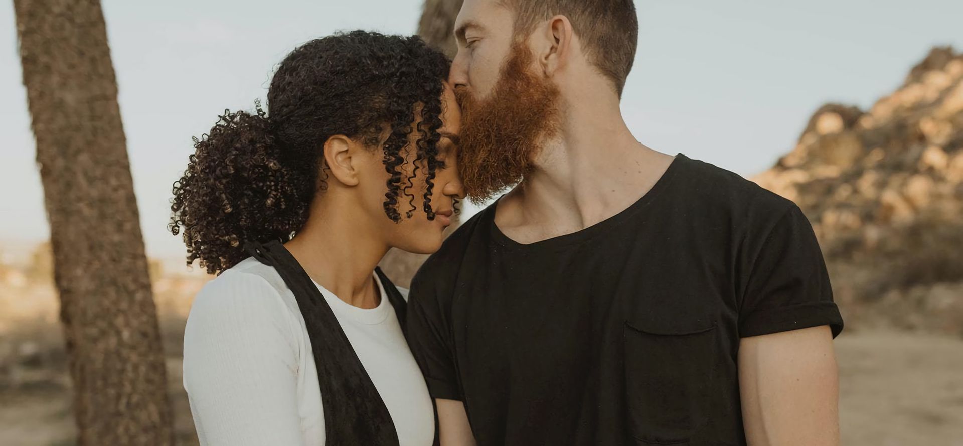 A man kisses a woman on the forehead.