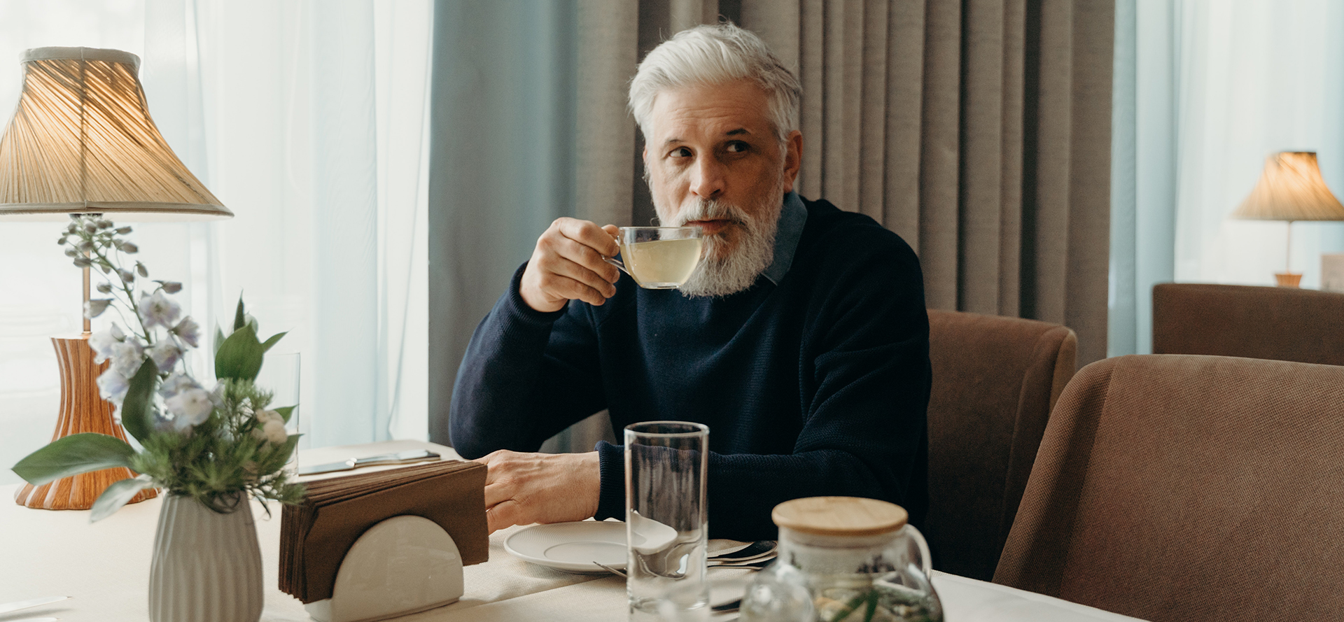 Un hombre mayor soltero está bebiendo té.