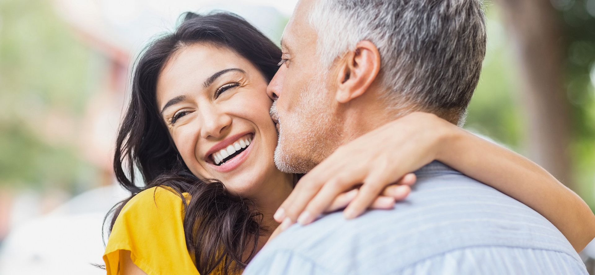 Older man kisses young woman.