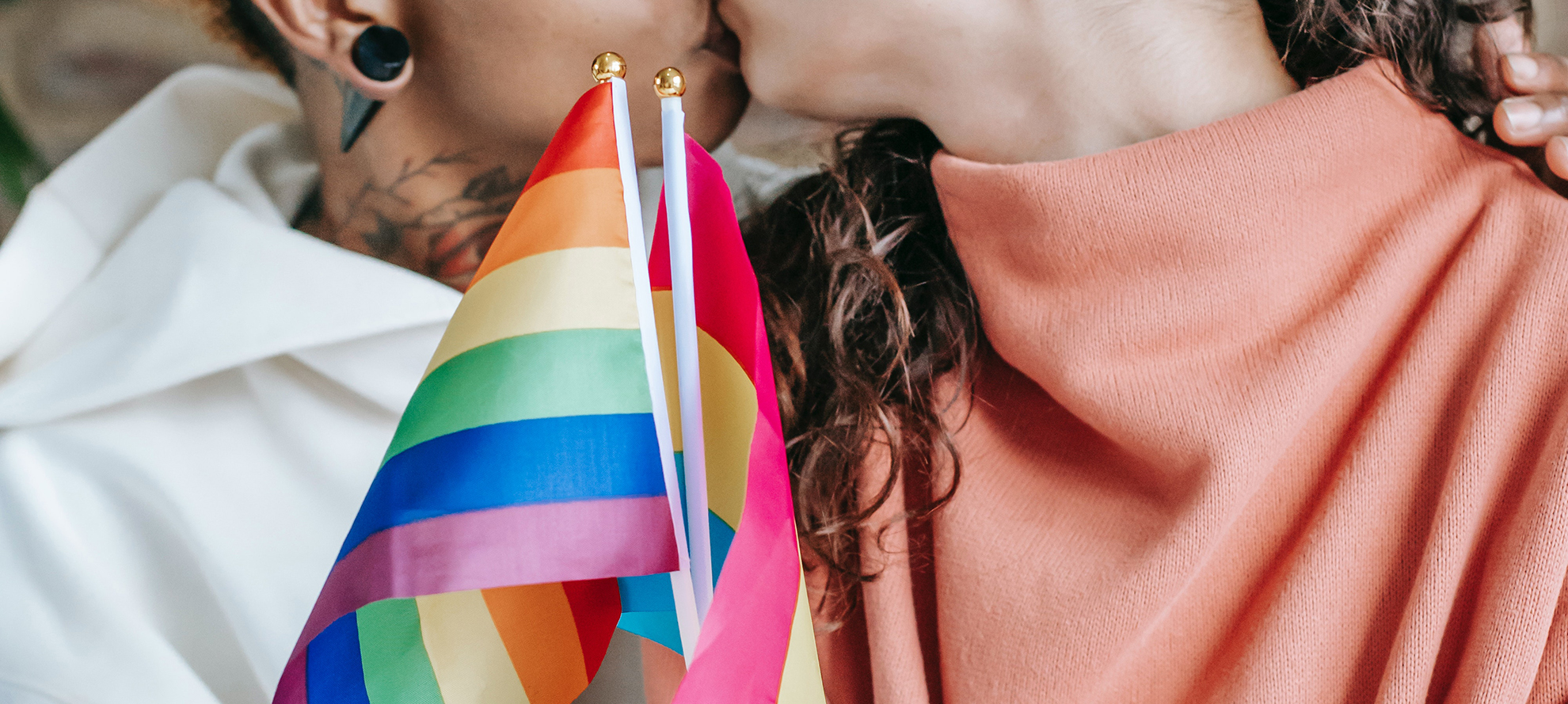 Kissing pansexual girls hold the lgbt flag.