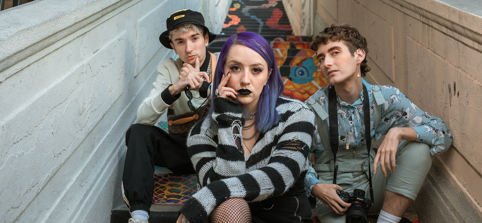 A girl with purple hair sits on the stairs with her friends.