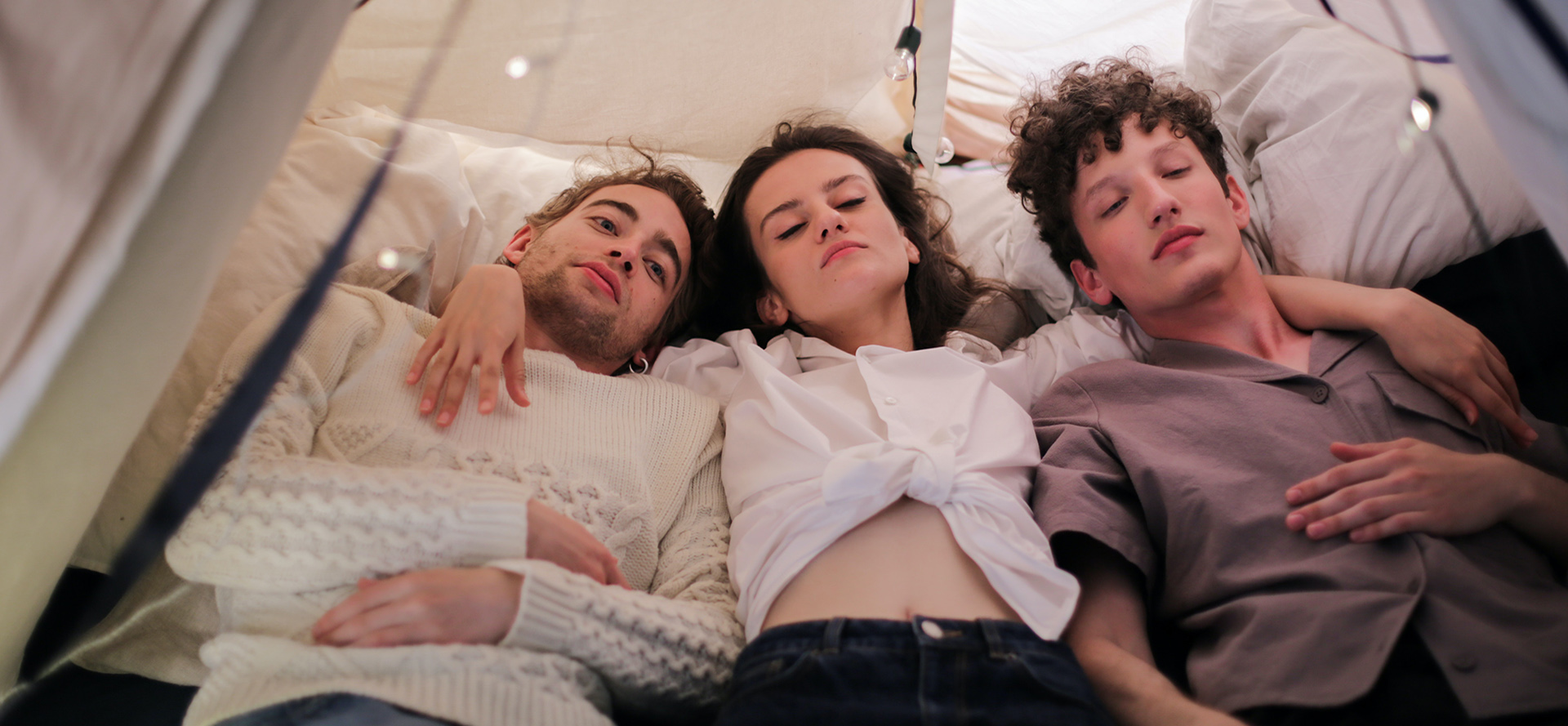 Polyamorous couple resting in a tent.