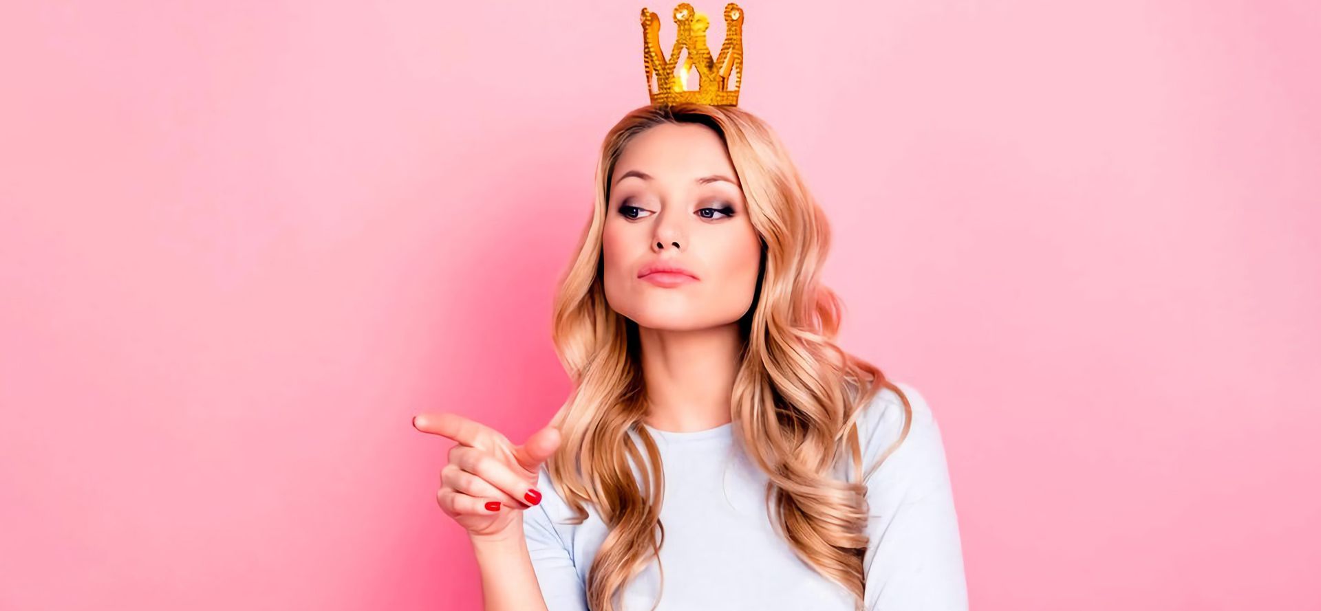 Girl on a pink background with a golden crown on her head.