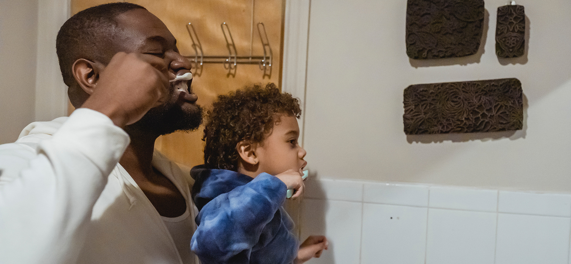 A single father teaches his son to brush his teeth.