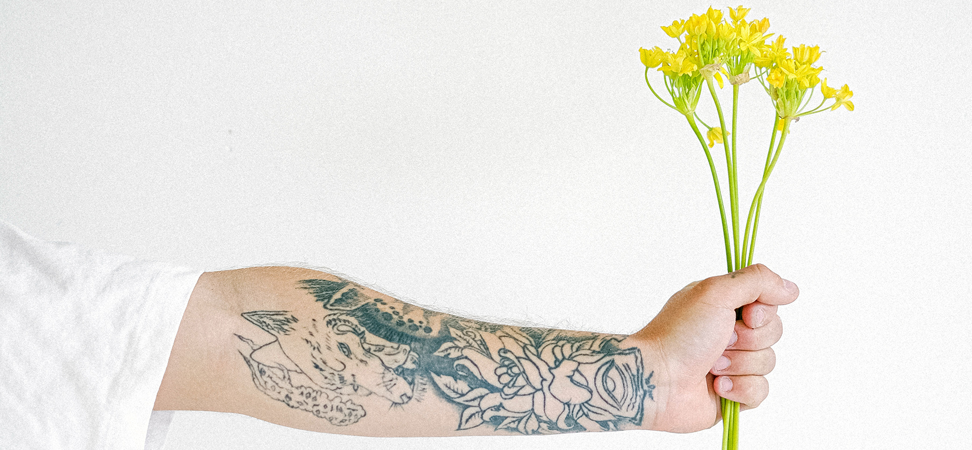 Tattooed arm holding bouquet.