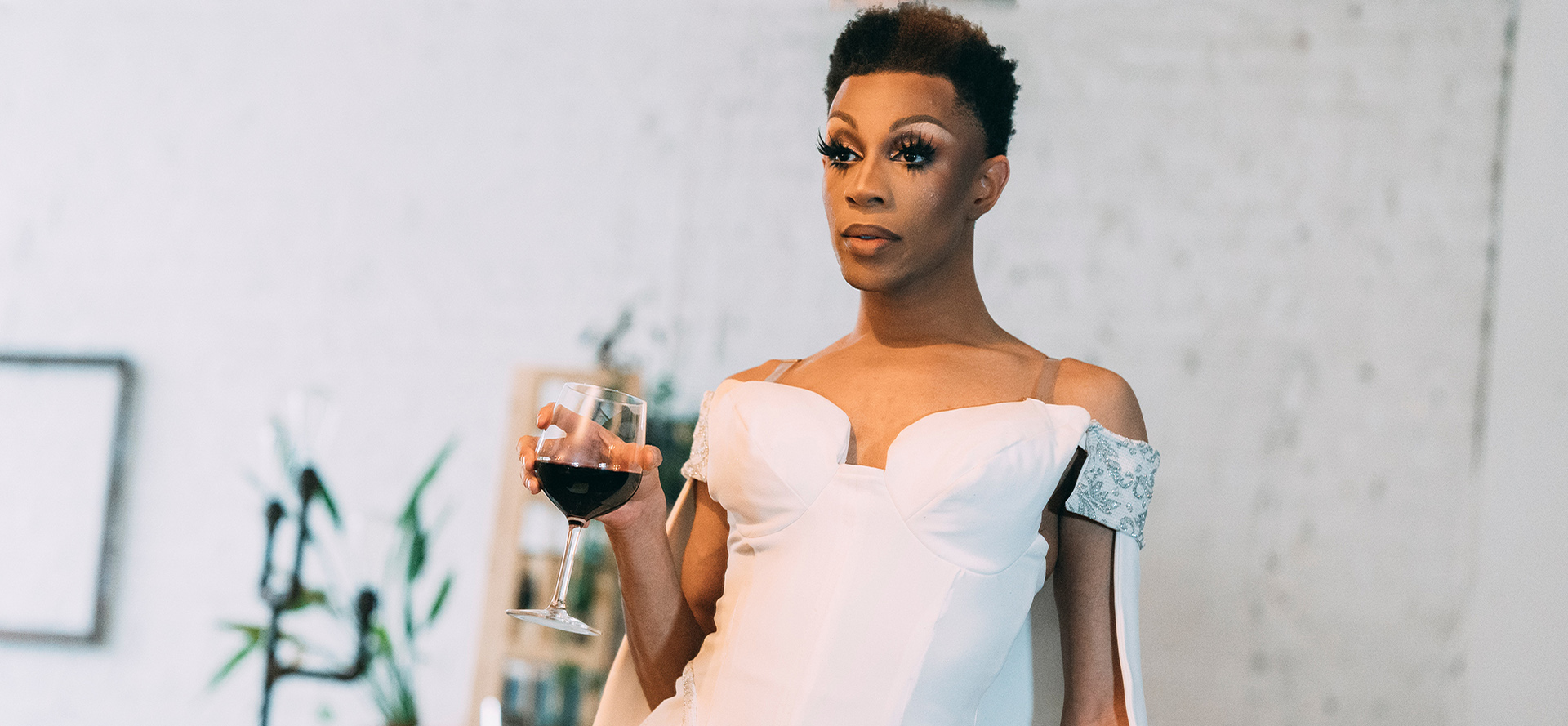 Transgénero en un vestido blanco con una copa de vino.