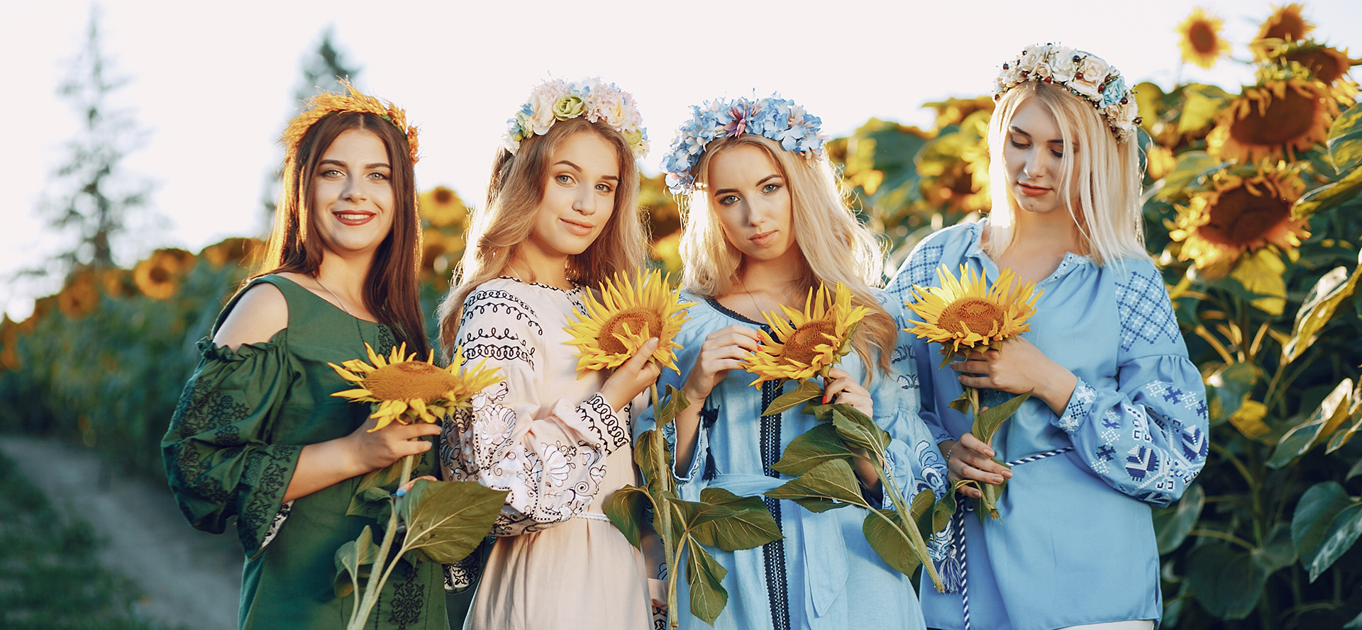 Vackra ensamstående ukrainska kvinnor med solrosor i händerna.
