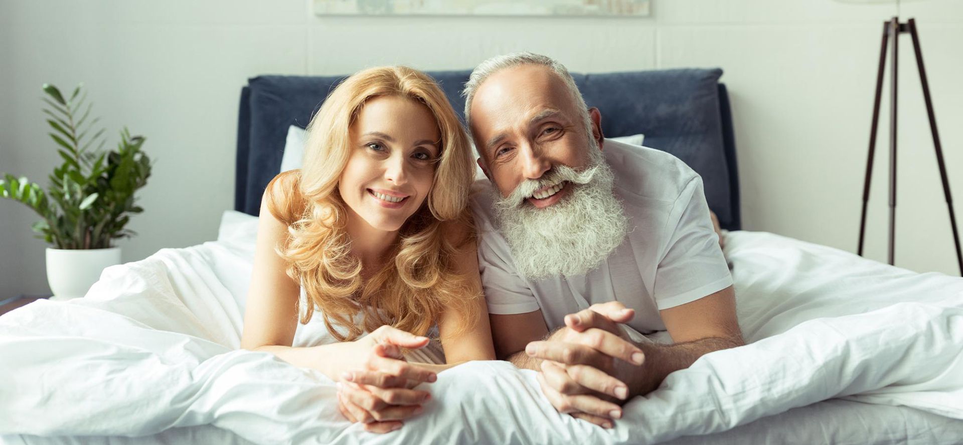 Young woman with older man lying on the bed.